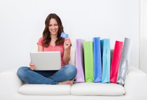 Young Woman Shopping Online Sitting Besides Row Of Shopping Bags